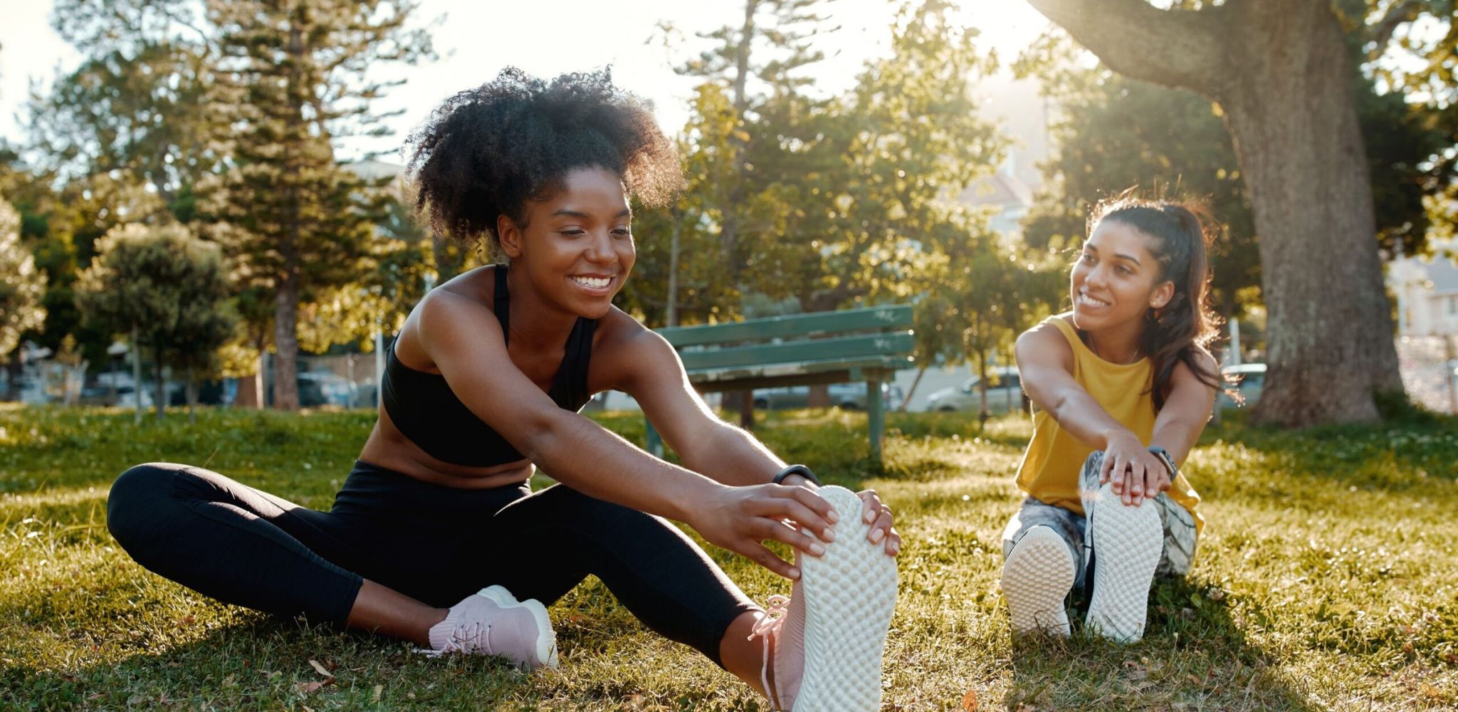Hawthorne at Green Valley female diverse friends doing stretching exercise in the park - diverse friends warming up before doing group exercise